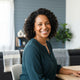 A friendly, smiling woman in a bright home interior with slate blue and charcoal decor, representing a satisfied customer.